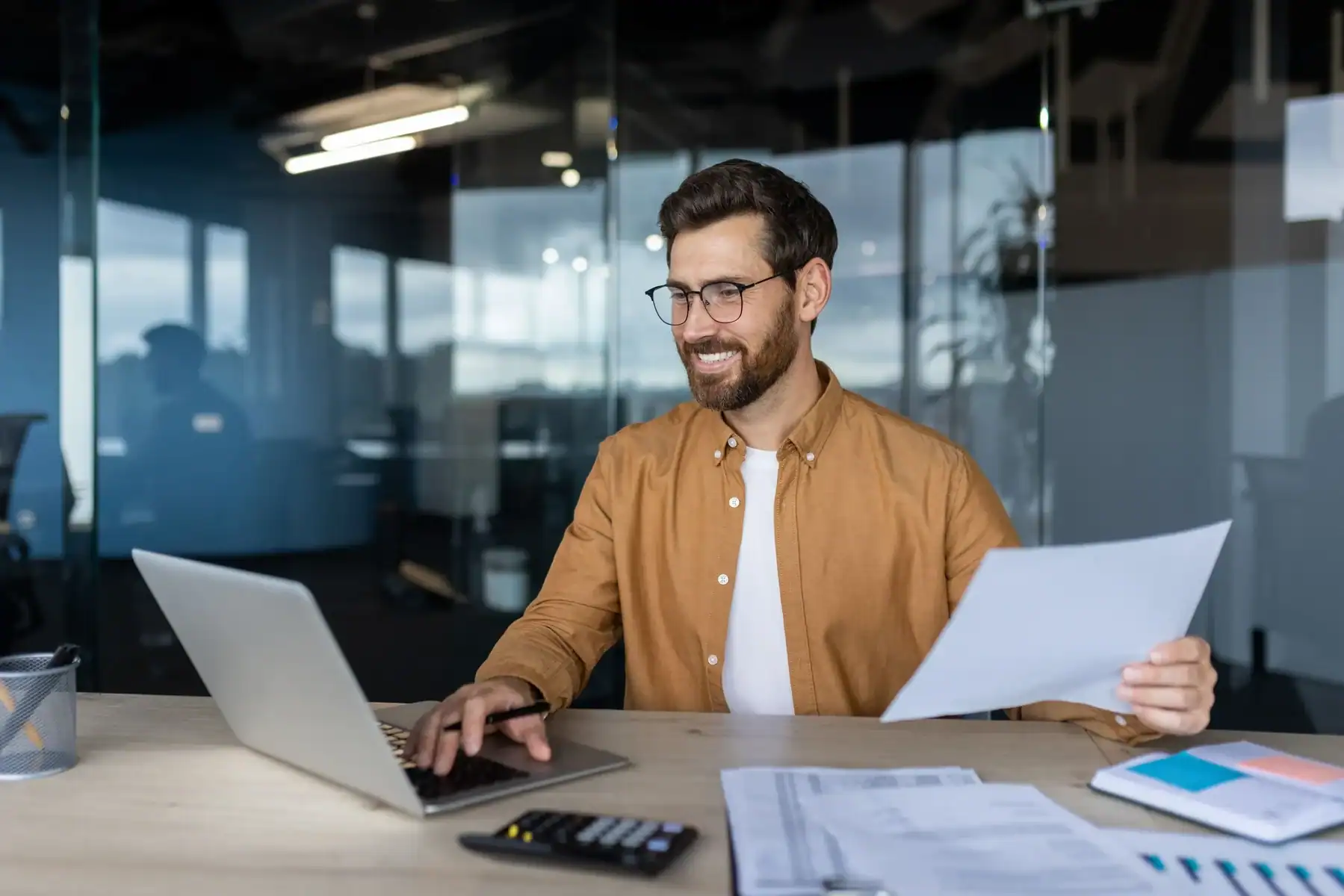Les métiers en vogue en France pour 2026 Homme d'affaires souriant avec documents et ordinateur portable.