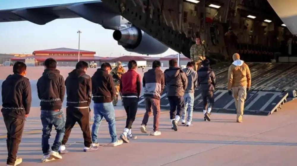 Groupe de migrants montant à bord d'un avion militaire.