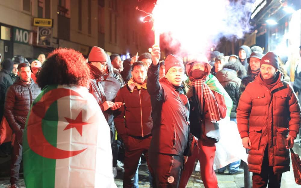 Manifestants algériens avec drapeau et fumigènes lors d'une protestation.