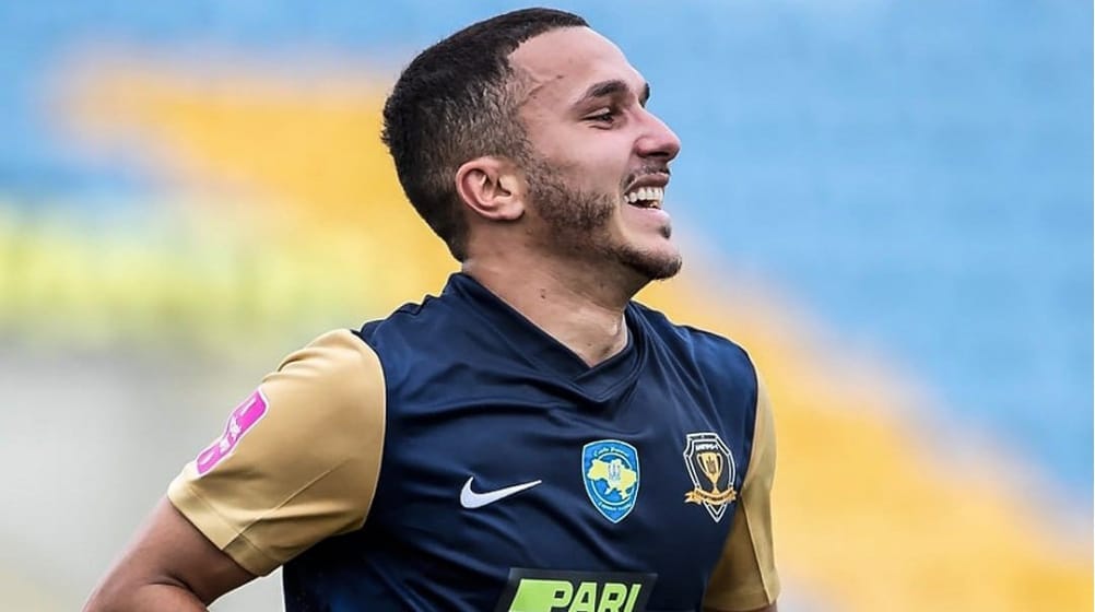 Yanis Hamache souriant en tenue de football sur le terrain.