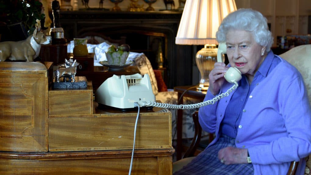 Reine Elizabeth II parlant au téléphone dans un intérieur royal.