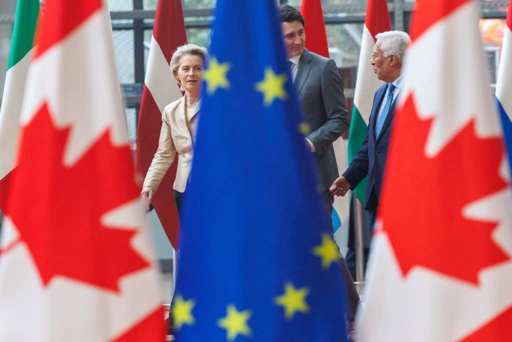 Rencontre entre dirigeants européens et canadiens avec drapeaux en arrière-plan.