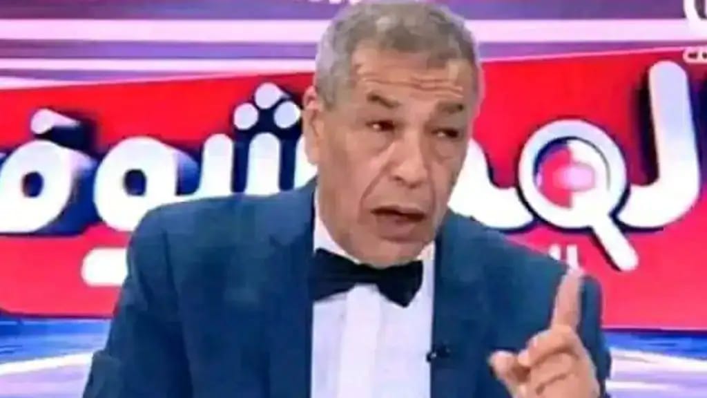 Ali Bencheikh en costume avec un fond rouge et blanc.