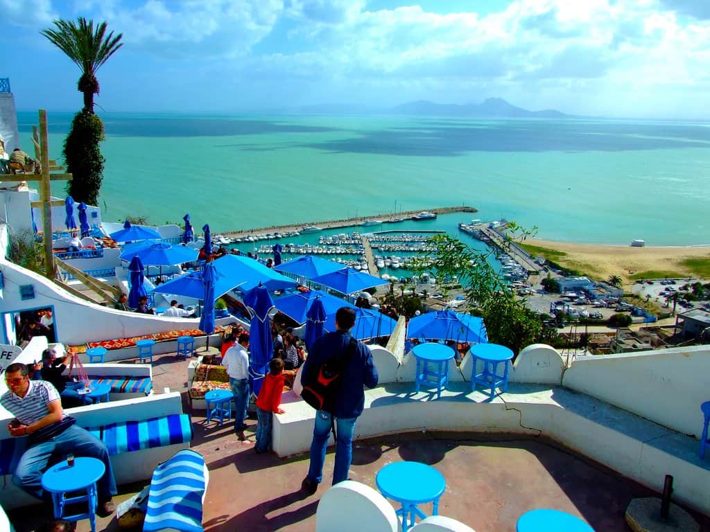 Vue de la mer en Tunisie avec terrasse et parasols bleus.