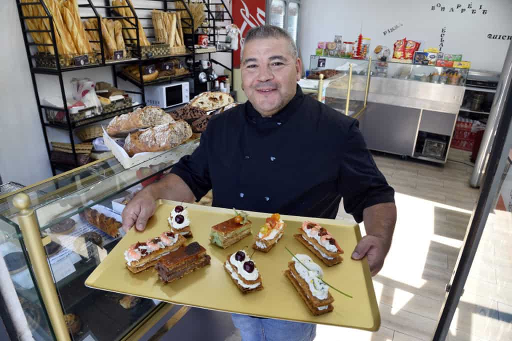 Akim Boughazi tenant un plateau de pâtisseries dans une boulangerie.