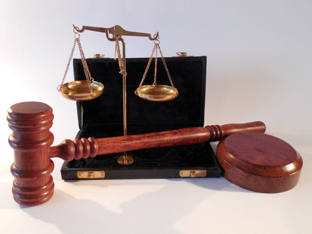 Nordine Aït Hamouda sous mandat de dépôt Balance de justice et marteau en bois, symbole juridique.