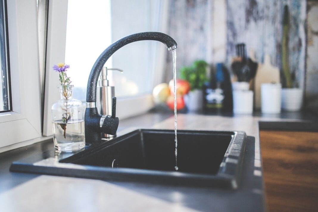 Robinet d'eau qui coule dans une cuisine lumineuse et moderne.