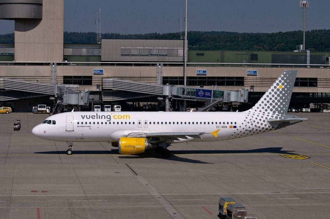 Avion Vueling à l'aéroport Avion Vueling stationné à l'aéroport avec terminal en arrière-plan.