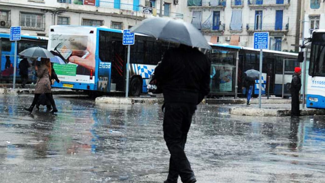 Météo chute de neige sur les reliefs dépassant les 900 mètres d’altitude Personne sous un parapluie dans une rue inondée en Algérie.