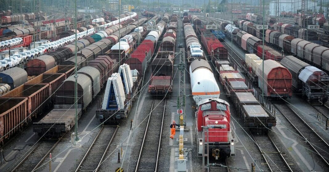 Vue d'une gare de trains avec plusieurs voies et wagons en attente.