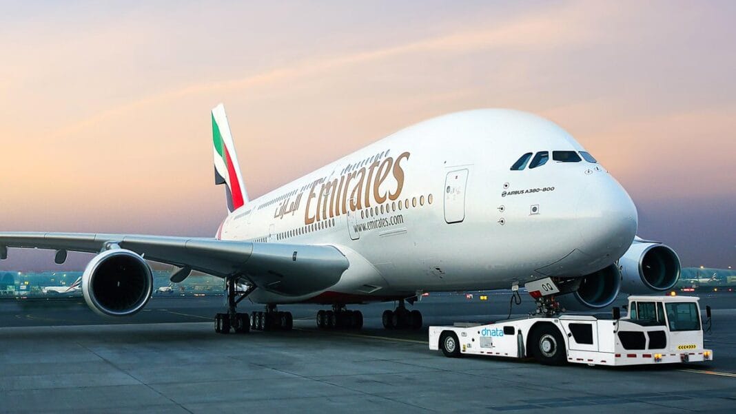 Emirates: Hausse des programmes de vols vers l’Algérie Avion Emirates Airlines blanc sur le tarmac au coucher du soleil.