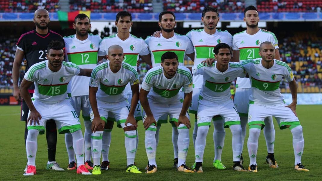 Groupe de joueurs de football algériens en tenue officielle sur le terrain.