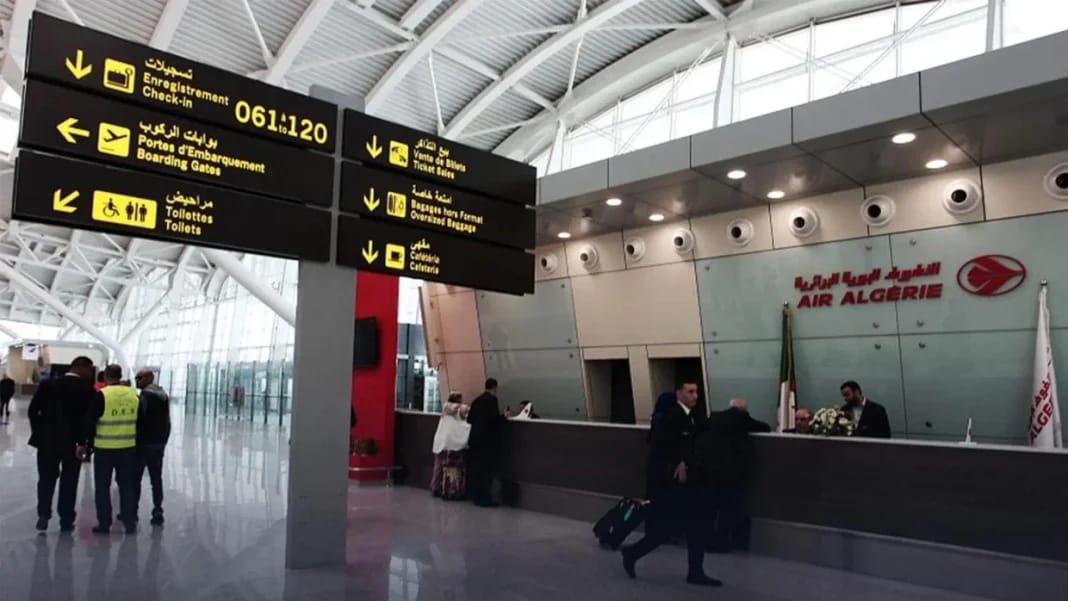 Zone d'accueil à l'aéroport d'Alger avec panneaux d'information.