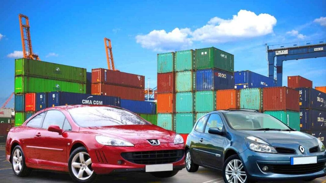 Voitures neuves et conteneurs dans un port maritime en plein jour.