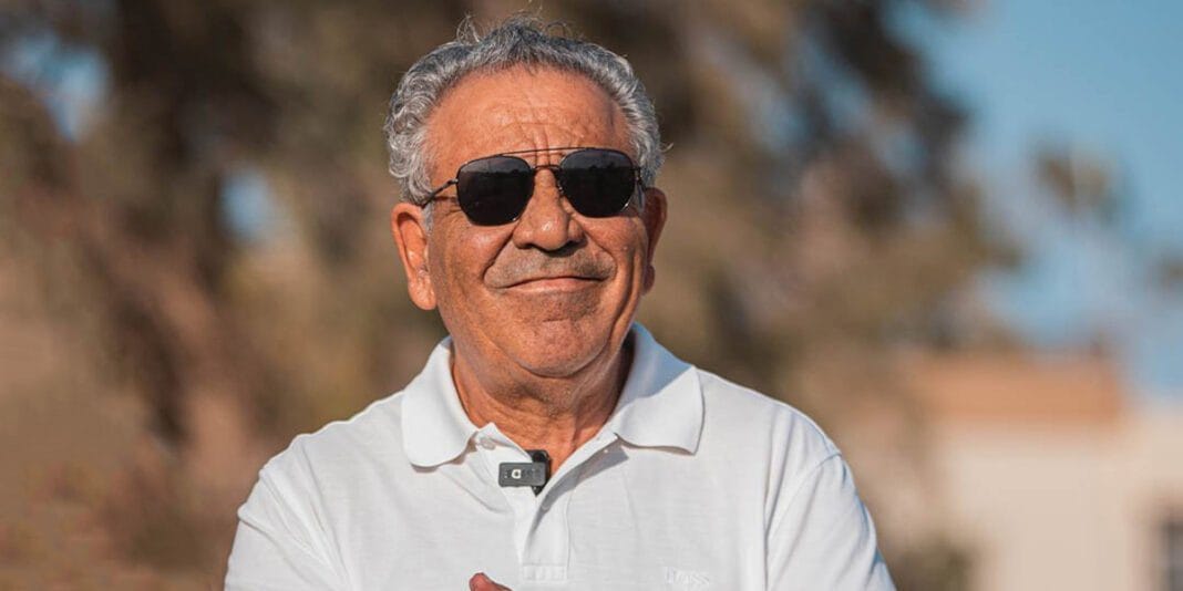 Homme d'entraînement de football avec lunettes de soleil et polo blanc.