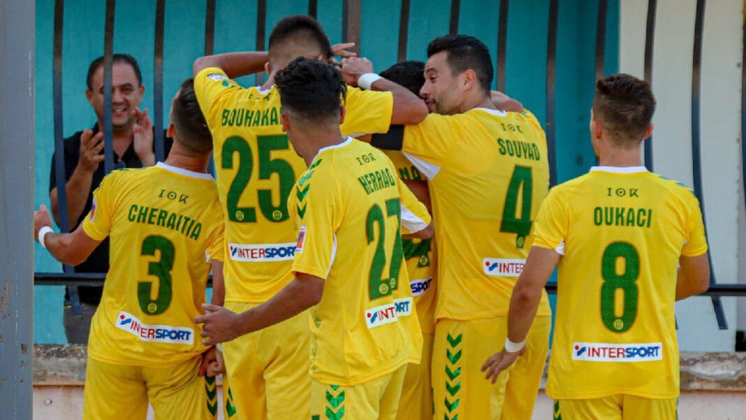 Équipe de football JS Kabylie lors d'un match, portant des maillots jaunes.