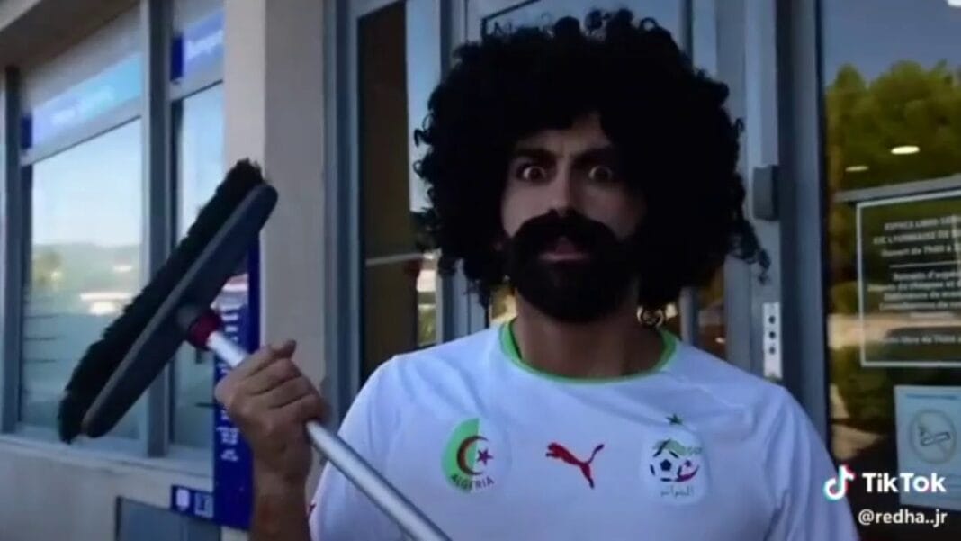 Humoriste avec perruque afro et canne, expression moqueuse.