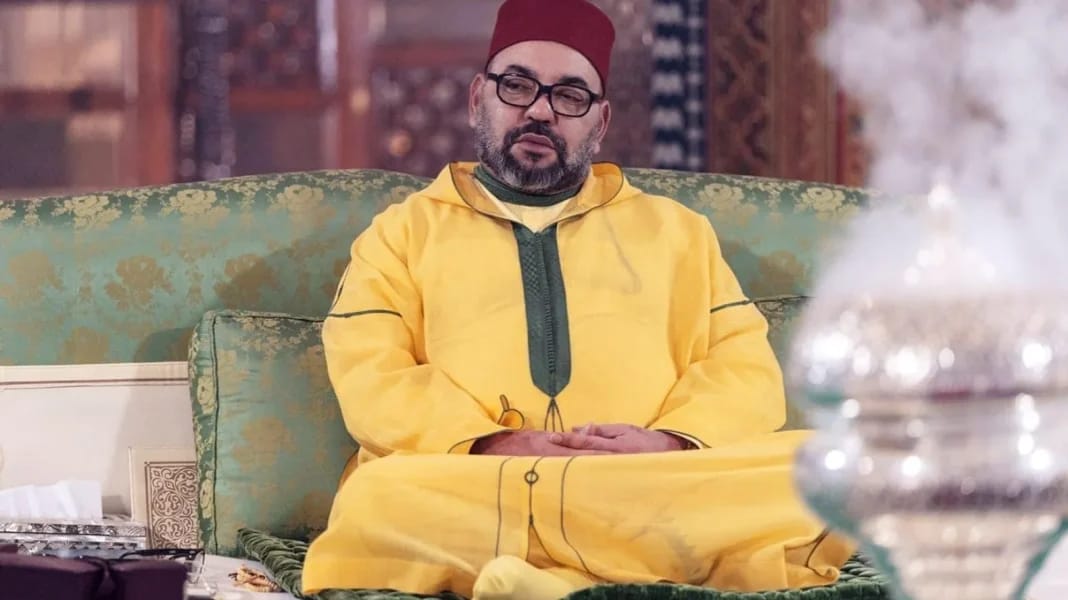 Homme en tenue traditionnelle marocaine assis sur un canapé.