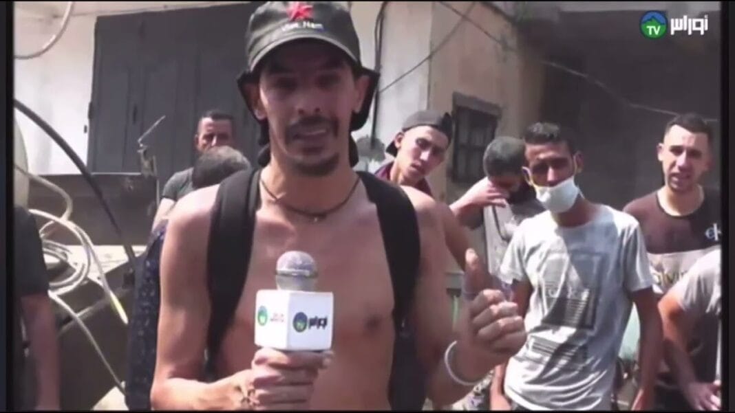 Homme en tenue décontractée parlant à la caméra lors d'une manifestation.