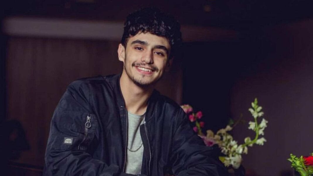 Algérie : Découvrez l’annonce surprenante de Stanley Jeune homme souriant portant une veste noire dans un environnement intérieur.
