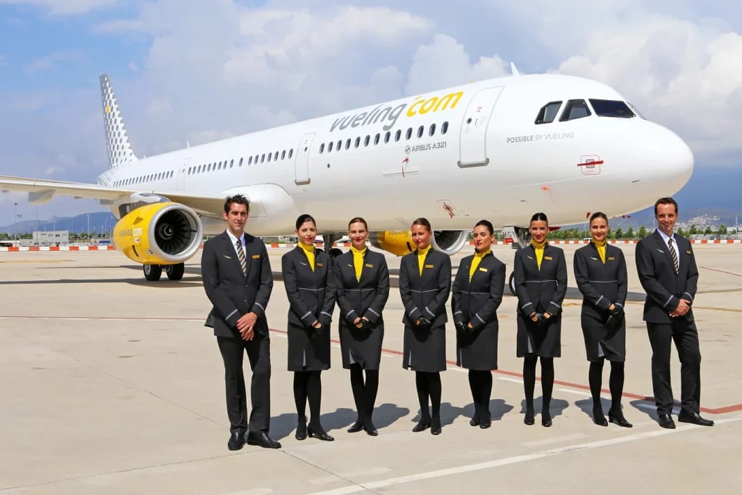 Personnel de Vueling en uniforme devant un avion à l'aéroport.
