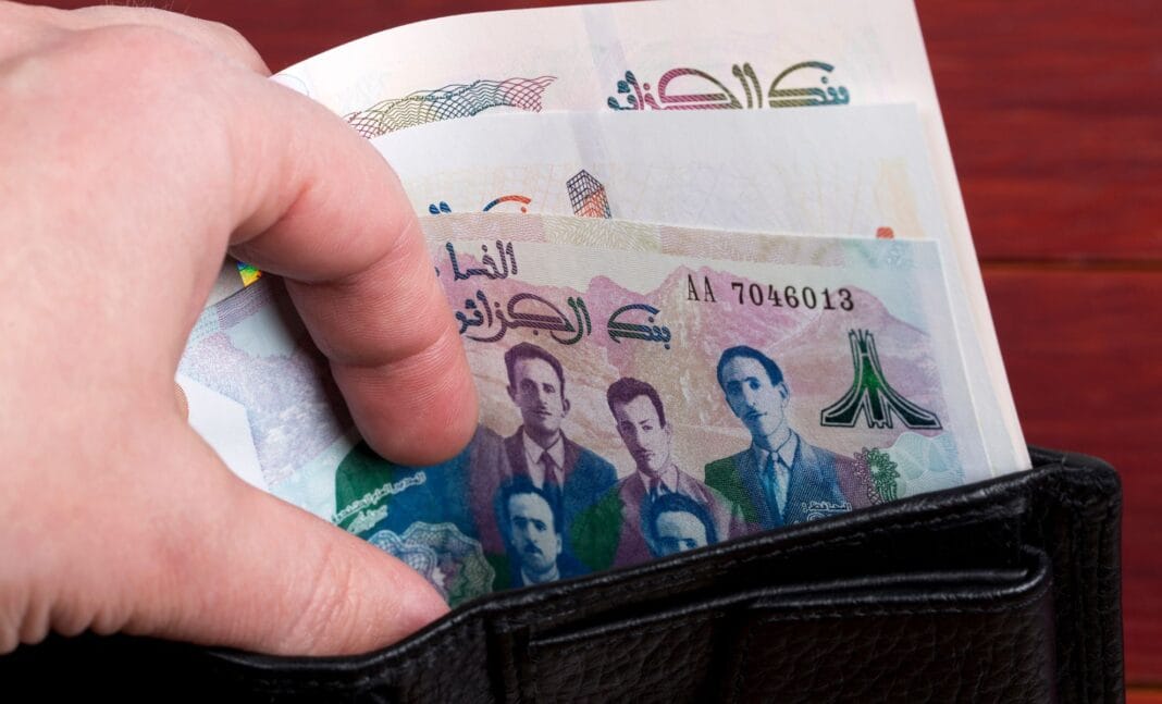 Femme mettant des billets de Dinar algérien dans un portefeuille.