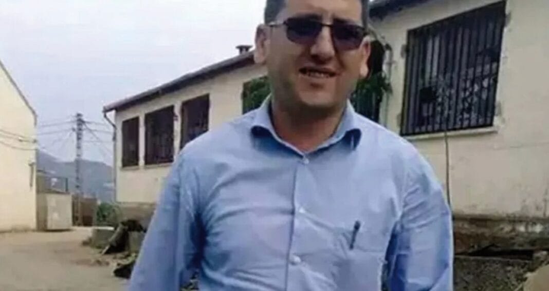 Homme portant une chemise bleue et lunettes de soleil dans un environnement urbain.