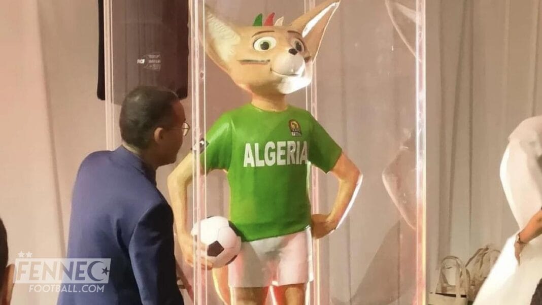 Mascotte de football en costume vert avec le nom 'ALGERIA' et un ballon.