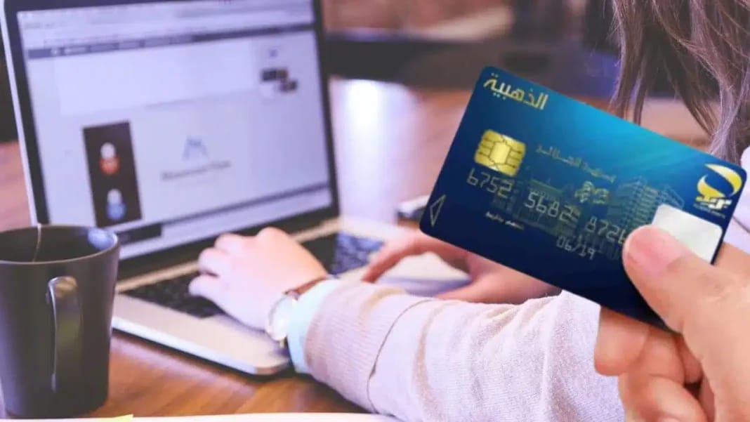 ECCP poste dz : Voici comment commander votre carte Edahabia en un clic Personne tenant une carte Edahabia devant un ordinateur portable.