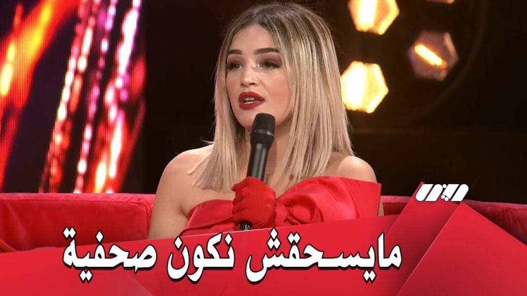 Inattendu ! Voici l’énorme surprise de Numidia Lezoul qui enflamme la toile Numidia Lezoul lors d'une interview, portant une robe rouge et tenant un micro.