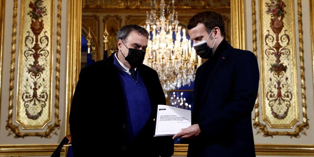 Deux hommes discutent dans un lieu élégant avec un chandelier.
