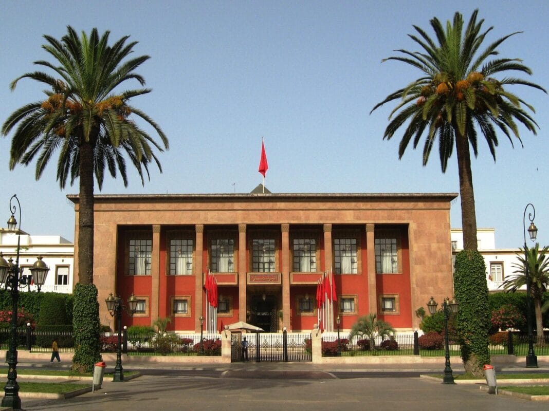 Palais royal marocain avec palmiers et drapeaux rouges.