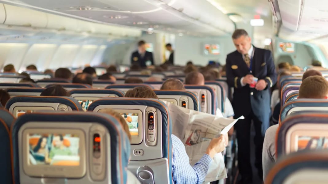 Passagers en avion avec un agent de bord vérifiant un passager.