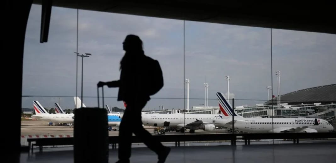 Passager avec valise à l'aéroport français, perturbations aériennes.