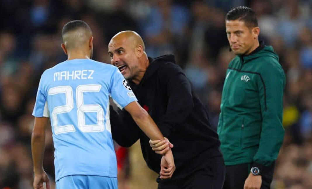 Mahrez et Guardiola en discussion Mahrez en conversation avec l'entraîneur Guardiola lors d'un match de football.