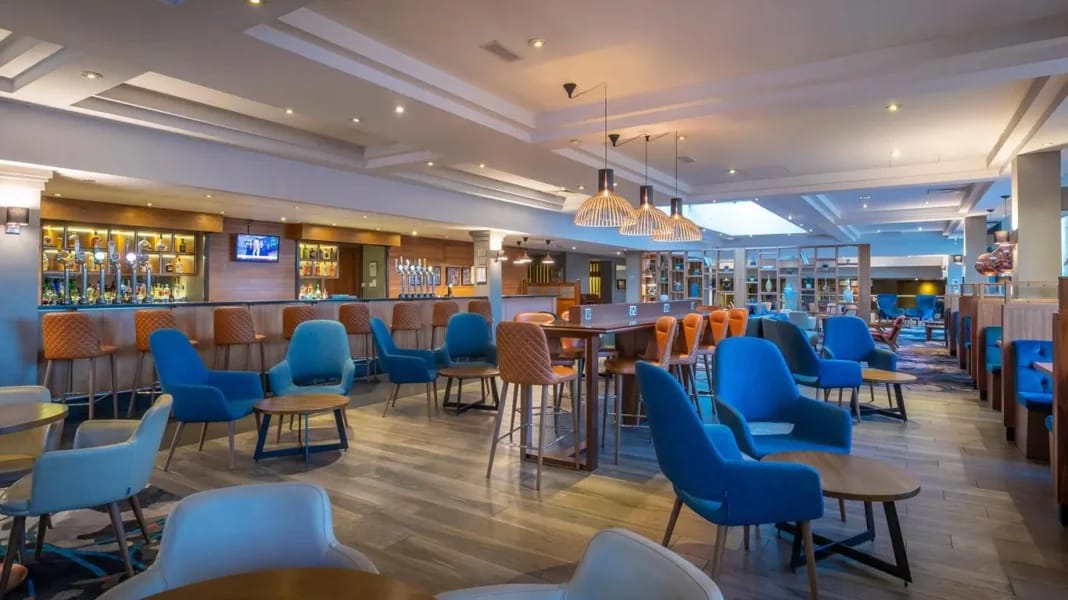Important! Dans un restaurant d’hotel, évitez de faire cette grave erreur, au risque de… Salon de restaurant d'hôtel avec chaises bleues et ambiance chaleureuse.