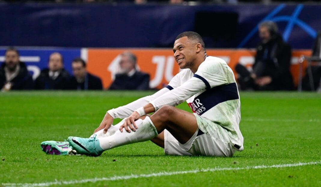 Kylian Mbappé assis sur le terrain après une blessure lors d'un match de football.