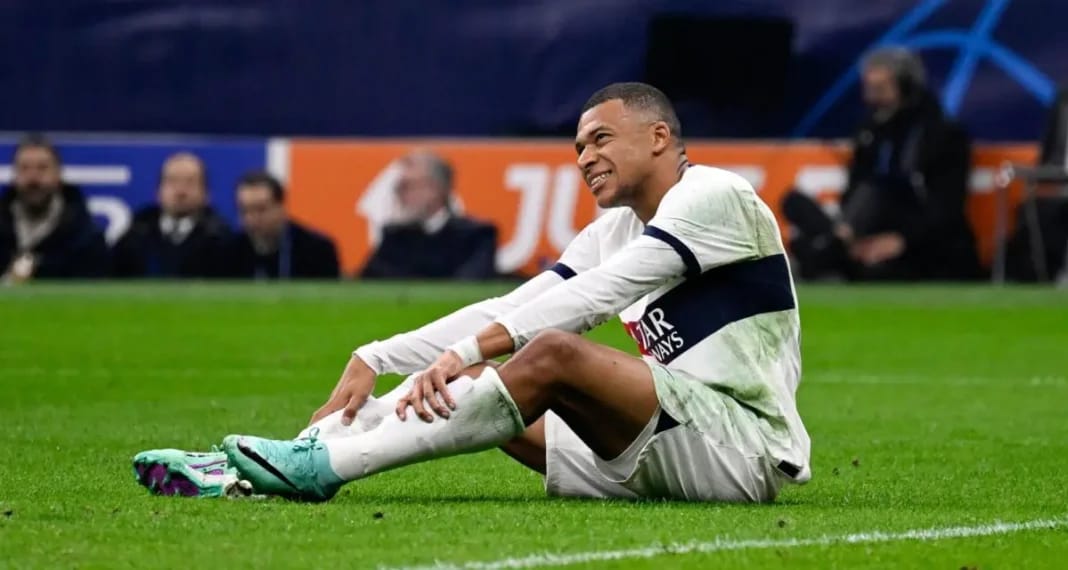 Kylian Mbappé assis sur le terrain après une blessure.