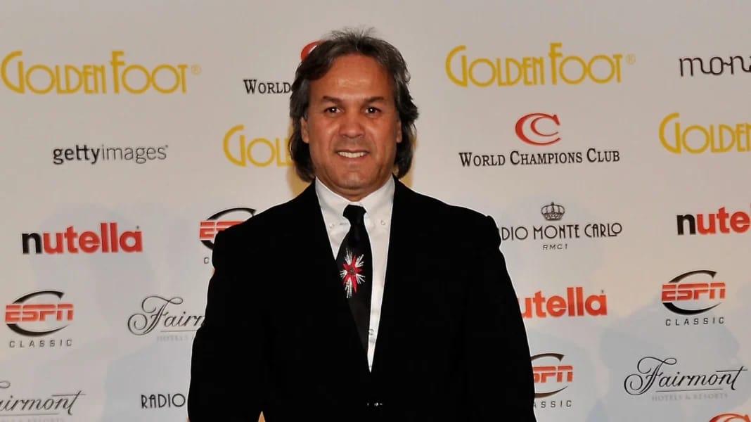 Rabah Madjer, Ballon d'Or africain 1987 Rabah Madjer lors d'une cérémonie, souriant, avec un fond de logos sportifs.