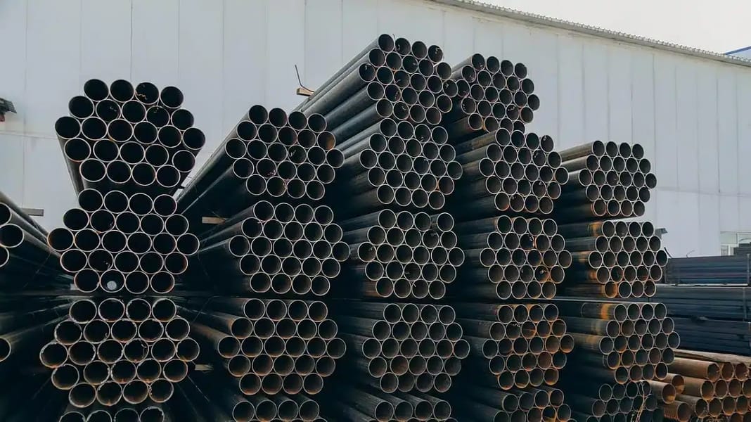 Exportations d’acier Algérien – USA : Un avenir incertain Tuyaux en acier noirs empilés dans une usine de fabrication.