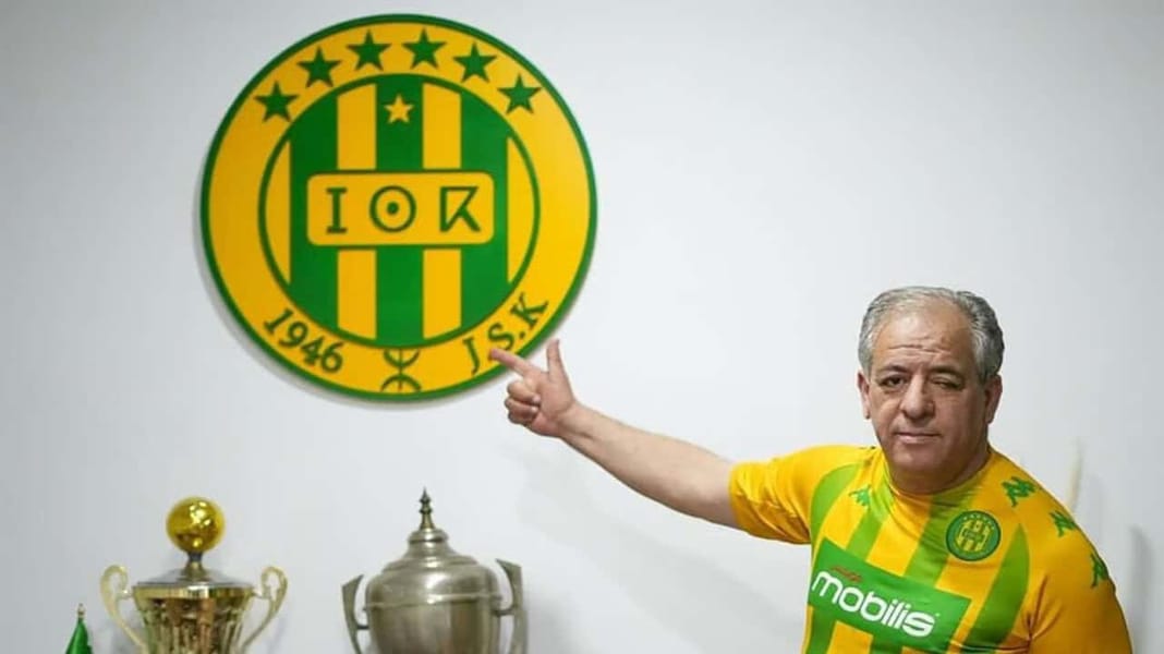 La JSK face à un ultimatum financier de 5 milliards Homme en maillot JSK Kabylie pointant le logo du club.