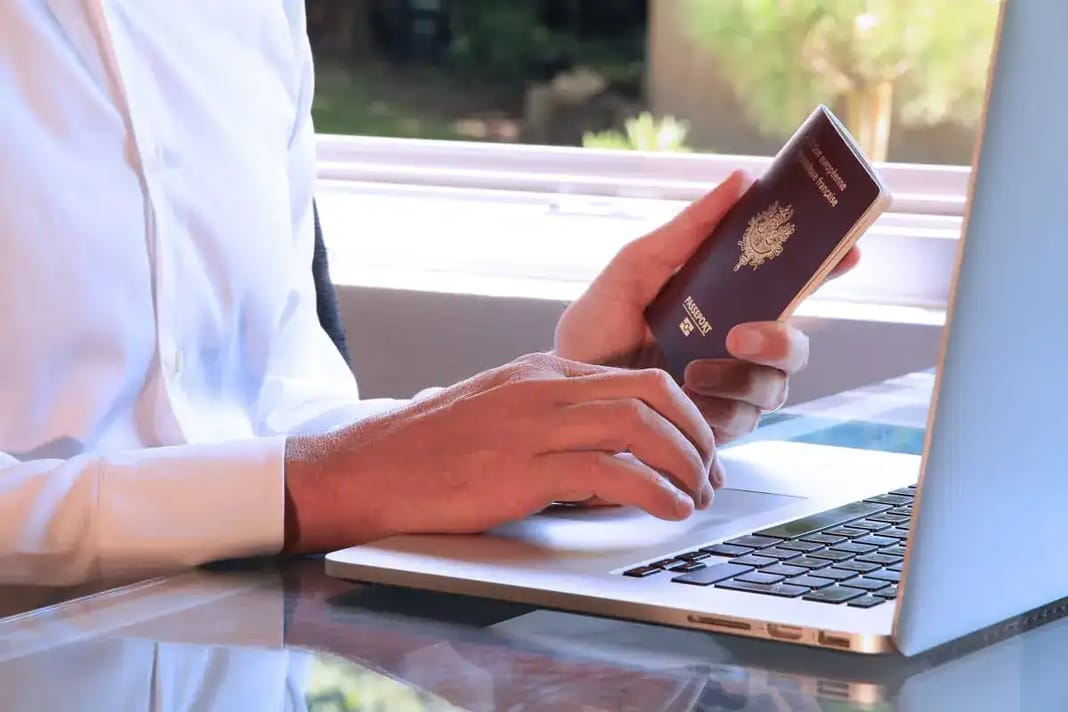 Visa algérien : la vraie raison de ce refus record en un jour Personne utilisant un ordinateur portable et un passeport pour demander un e-Visa.