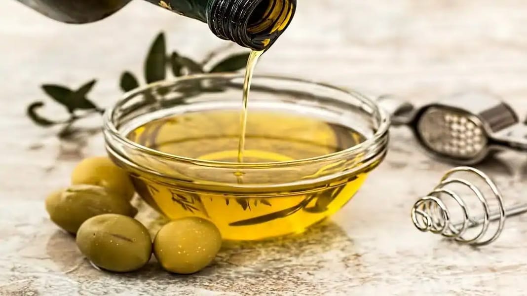 Huile d’olive algérienne bio : le pari du luxe au Canada Huile d'olive versée dans un bol avec olives vertes.