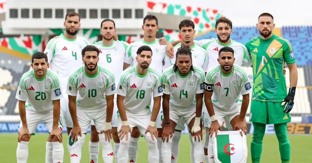 Groupe de joueurs de football algériens en tenue officielle sur le terrain.