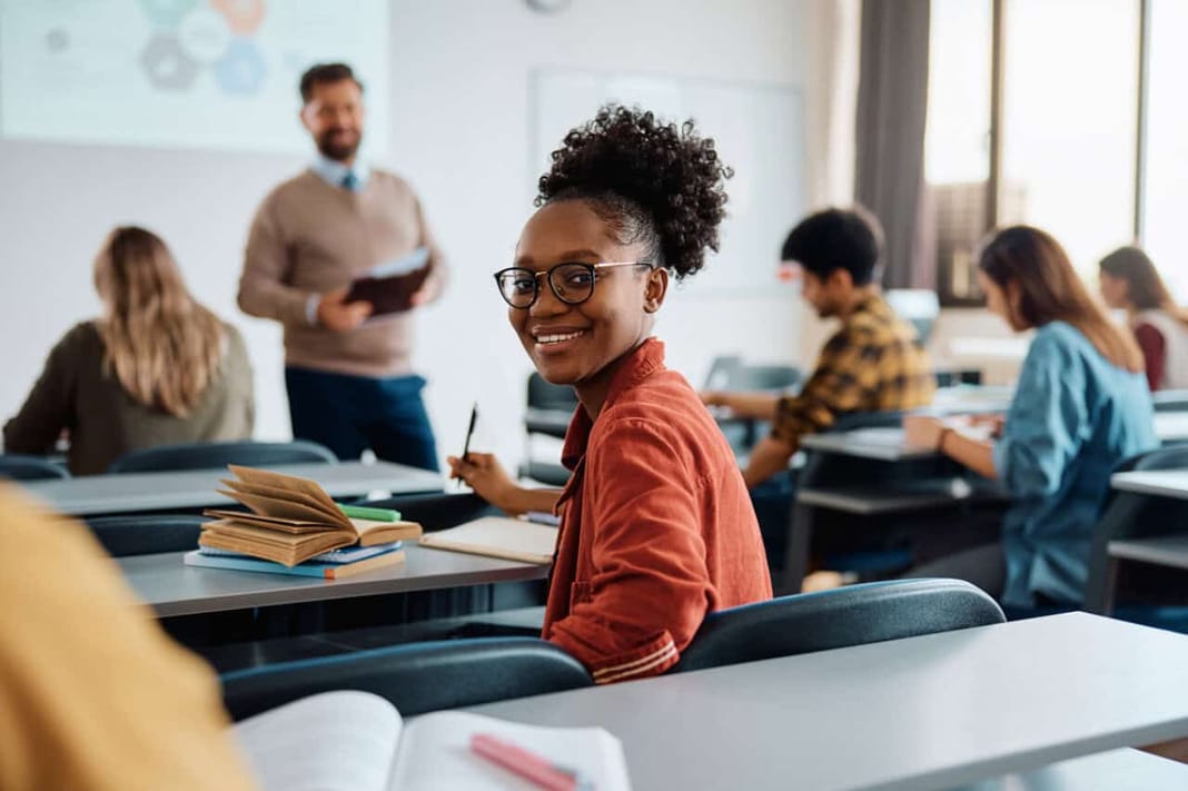 Étudiants étrangers en France : ce budget qui explose en 2025 Étudiante souriante en classe avec professeur et autres étudiants.