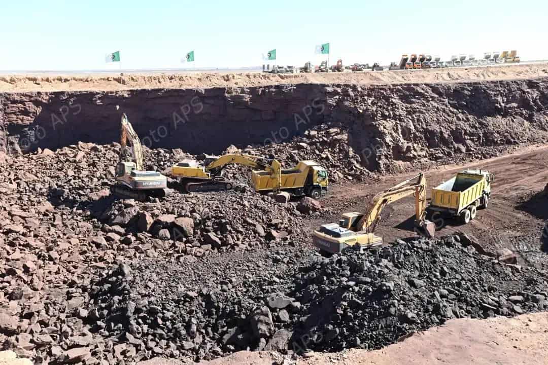 Travaux miniers à Gara Djebilet avec excavatrices et camions.