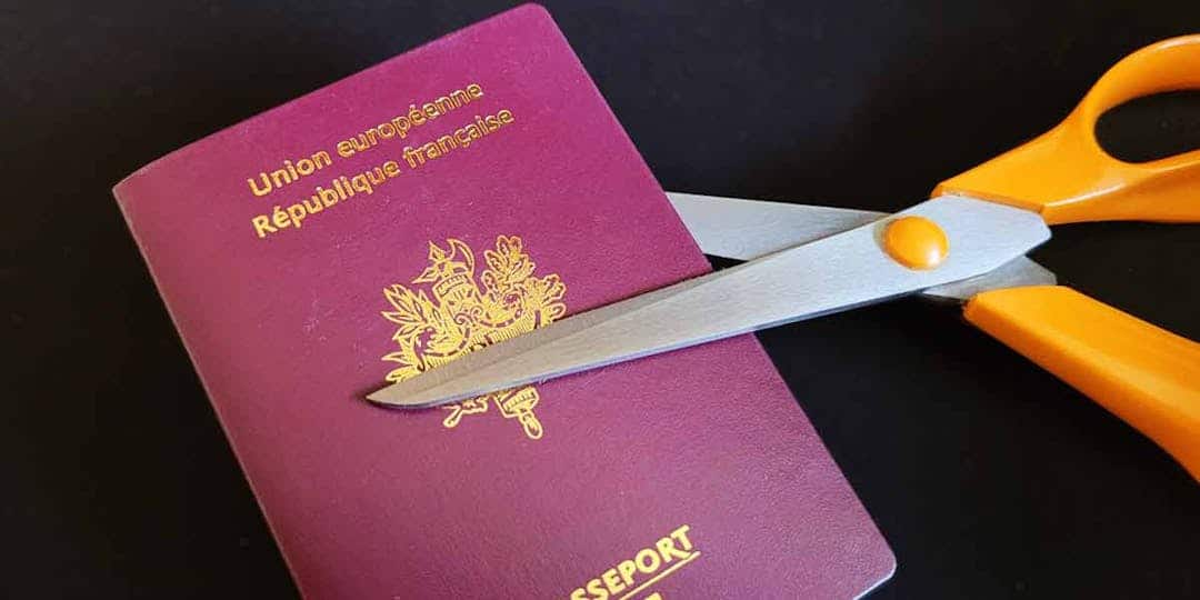 Ciseaux coupant un passeport français avec le drapeau français.