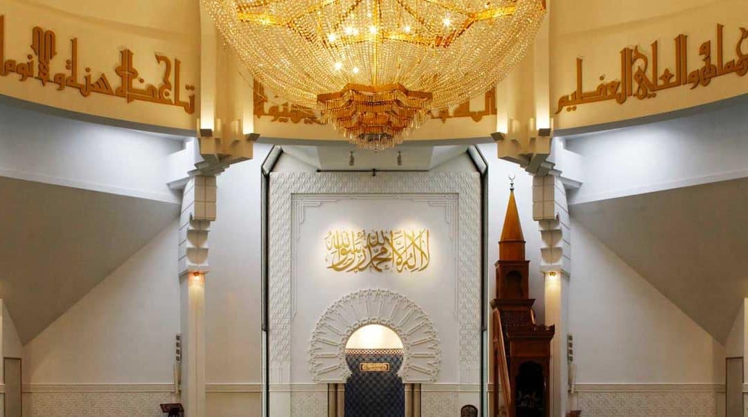 Vue intérieure d'une mosquée avec un chandelier et calligraphies arabes.