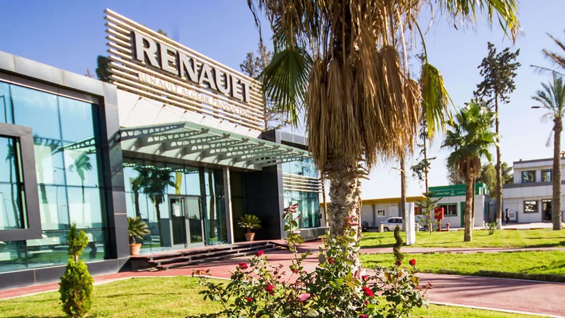 Usine Renault en Algérie avec palmiers et bâtiment moderne.