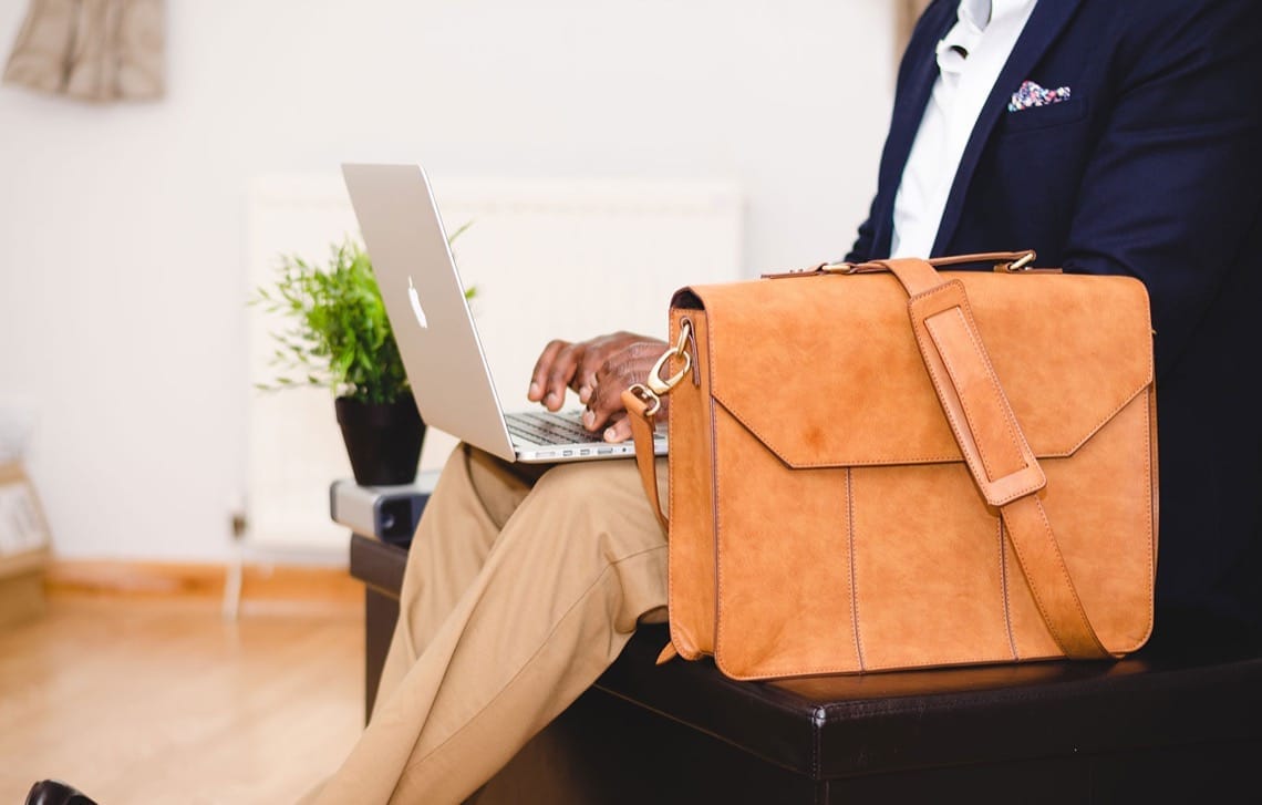 Homme d'affaires utilisant un ordinateur portable avec un sac en cuir marron.